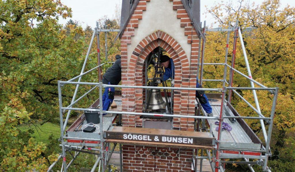 Uwe Griwahn (r.) und sein Kollege bei der Montage der Glocke im Turm der Trauerkapelle, Foto: formWeb.de/H.Woitendorf