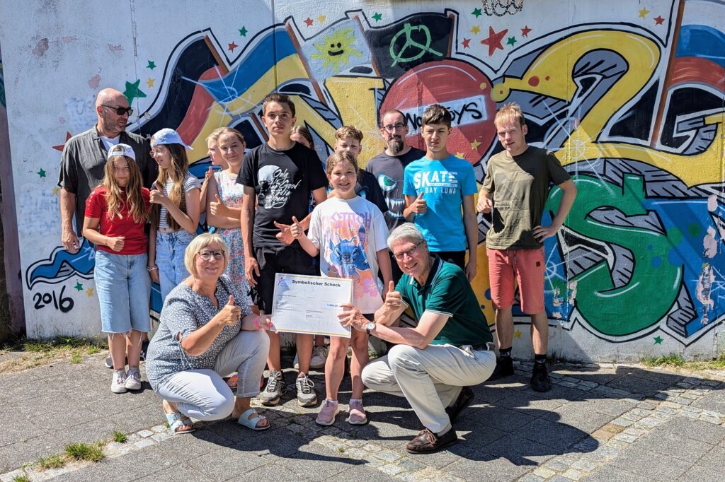 Der stellvertretende Vorstandsvorsitzende der Bürgerstiftung, Stephan Nolte übergibt den symbolischen Scheck an Ute Klahre (Projektverantwortliche beim DRK Kreisverband Schwerin e. V.), ihr Team und ihre Freizeitkinder.